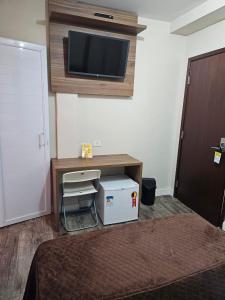 1 dormitorio con escritorio y TV en la pared en Bella Augusta Hotel, en São Paulo