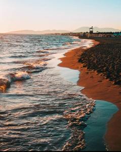 una playa con el océano y un faro a lo lejos en Guesthouse Domenik en Ulcinj