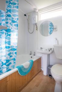 Un baño con bañera, lavabo e inodoro. en Milkwood, en Llangain