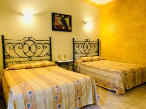 2 camas en una habitación con paredes amarillas en Hotel Beddo Express Querétaro en Querétaro