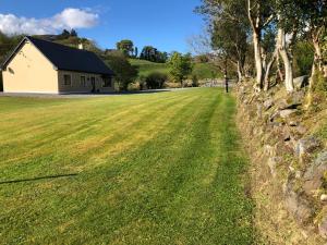 a field with a stone wall and a house at Lissyclearig Lodge in Kenmare