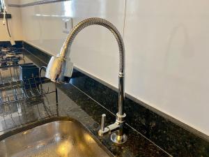 een gootsteen met een metalen kraan bij Condomínio Edifício Viena in Vila Balneária +21 foto's