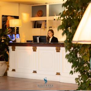 Una donna seduta al bancone in un salone di Hotel Sinuessa Terme a Mondragone