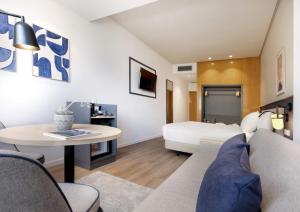 a living room with a bed and a table at Hotel Málaga Alameda Centro Affiliated by Meliá in Málaga