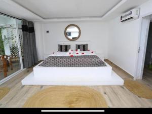 a bedroom with a large white bed and a mirror at Ayras Hotel Zanzibar in Paje