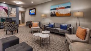 a living room with couches and chairs and a tv at Best Western St. Louis Airport North Hotel & Suites in Hazelwood