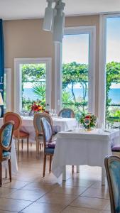 una sala da pranzo con tavoli e sedie bianchi e finestre di Hotel Sinuessa Terme a Mondragone
