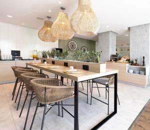 a dining room with a table and chairs and chandeliers at Hotel Málaga Alameda Centro Affiliated by Meliá in Málaga