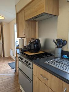 a kitchen with a stove and a stove top oven at Lyons Robin Hood Holiday Park - Private Caravans with PS5 and WiFi in Meliden