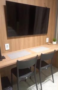 a desk with two chairs and a large screen at Studio Campo Belo 301 in Sao Paulo
