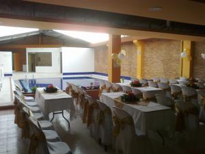 un salón de banquetes con mesas y sillas blancas en Hotel Tropico Real Mesitas, en El Colegio