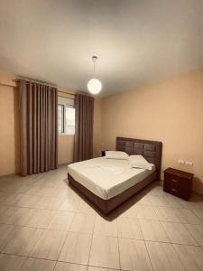 a bedroom with a large bed and a lamp at Heraklius Apartament in Sarandë