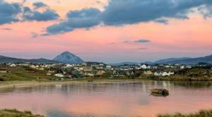 a lake with a town and a mountain in the background at Dungloe Lakeside Lodging in Dungloe