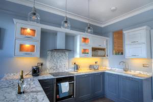 une cuisine avec des murs bleus et des armoires blanches dans l'établissement The Eastleigh, à Seaton