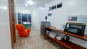 Liturs Travel Services / Homestay / Rent a Car في باكولود: غرفة معيشة مع كرسي برتقالي وميكروويف