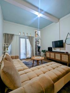 ein Wohnzimmer mit einem großen Sofa und einem TV in der Unterkunft Homestay Lingga Yoni DIENG in Banjarnegara