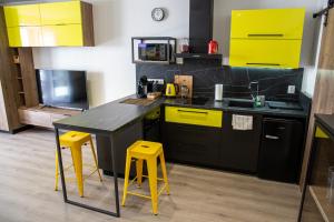kuchnia z żółtymi i czarnymi szafkami oraz żółtymi stołkami w obiekcie Apartmán Yellow Submarine se slunnou terasou w mieście Kutná Hora
