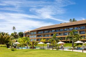 a hotel with a lawn and umbrellas in front of it at Vista Linda Eco Resort Carneiros in Tamandaré