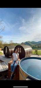 a woman sitting on a table next to a tub at Glamping Il Rifugio dei Marsi in Ascoli Piceno