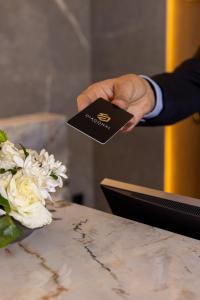 a man is holding a business card at a table at DIAGONAL HOTEL in Tangier