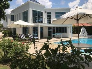 uma casa branca com piscina e guarda-sóis em Condominio El Peñon, Girardot em El Peñón mais 9 fotografias