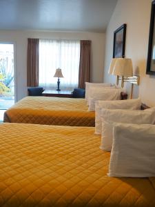 Habitación de hotel con 2 camas con sábanas amarillas en Wild Rivers Motorlodge, en Brookings