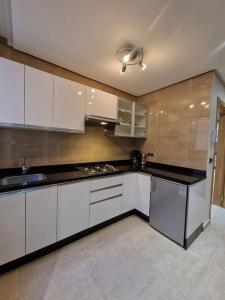 a kitchen with white cabinets and a black counter top at Hotel Residence Ramsis in Nador