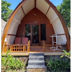 an arched entrance to a wooden cabin with two chairs at We'Be Cottages in Gili Meno