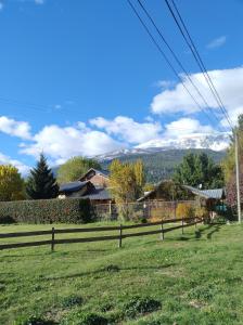 a field with a fence and mountains in the background at Casa de Silvina in El Bolsón