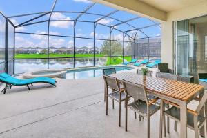 a patio with a table and chairs and a pool at 6BR Luxury Home w Pool Hot Tub and Games room in Kissimmee +31 photos