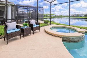 a patio with wicker chairs and a swimming pool at 6BR Luxury Home w Pool Hot Tub and Games room in Kissimmee