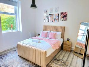 een slaapkamer met een groot bed met roze kussens bij Spacious Haven with Free Parking in Glasgow