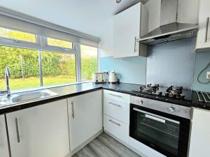 een keuken met witte kasten, een wastafel en een raam bij Spacious Haven with Free Parking in Glasgow