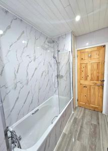 een badkamer met een bad en een marmeren muur bij Spacious Haven with Free Parking in Glasgow