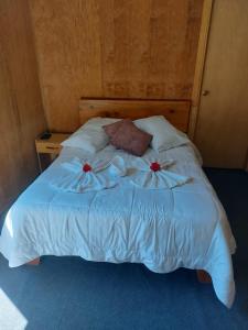 Una cama con sábanas blancas y almohadas rojas. en Tangara Lodge, en San Gerardo de Dota