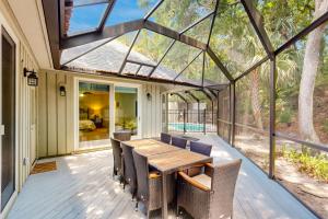 a conservatory with a wooden table and chairs on a deck at 13 Green Winged Teal in Fernandina Beach