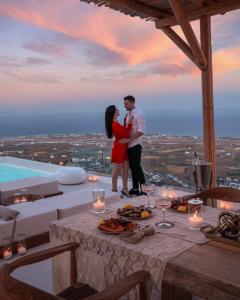 a man and a woman standing on top of a building at Bluewhite Villa Santorini in Pyrgos