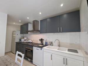 a kitchen with white cabinets and black appliances at Maison de Bourg Rénovée avec Jardin et Salle de Jeux à Levroux - FR-1-591-204 in Levroux
