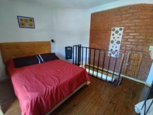 a bedroom with a bed with red sheets and a brick wall at Cabañas La Soleada in Potrero de los Funes