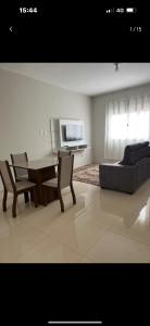 een woonkamer met een tafel, stoelen en een bank bij Apto Nossa Senhora Aparecida in Aparecida