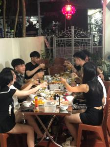 un grupo de personas sentadas alrededor de una mesa comiendo comida en HT Homestay Cát Bà en Cat Ba