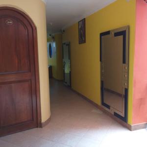 un couloir vide avec une porte en bois et des murs jaunes dans l'établissement Hotel karol, à Ayacucho