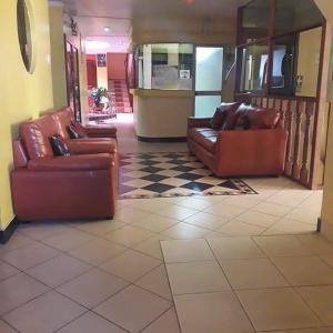 vestíbulo con 2 sofás de cuero marrón y suelo a cuadros en Hotel karol en Ayacucho