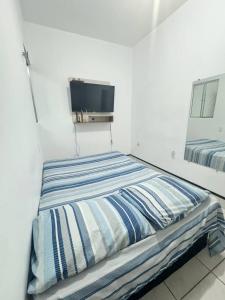 a bed in a white room with a tv on the wall at Ap próximo ao Arco com garagem in Sobral