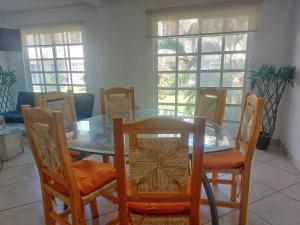 une salle à manger avec une table et des chaises en verre dans l'établissement Casa Azur- vista al mar y alberca, à Acapulco