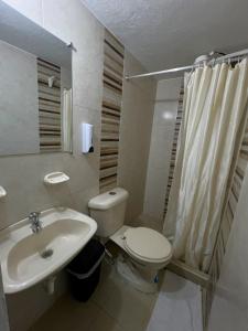 La salle de bains blanche est pourvue de toilettes et d'un lavabo. dans l'établissement Anhyali Hospedaje, à Villa de Leyva