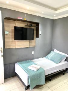 a bedroom with a bed with a flat screen tv on the wall at Pousada Recanto Beach House - Cabo Frio - Unamar in Tamoios