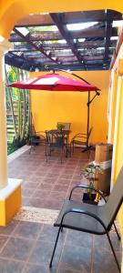 eine Terrasse mit Tischen und einem roten Regenschirm in der Unterkunft La Maison BLEUE in Cancún