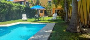 einen Pool mit einem Sonnenschirm, Stühlen und einem Tisch in der Unterkunft La Maison BLEUE in Cancún