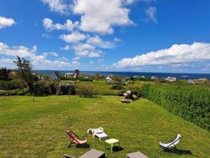 dos sillas y mesas en un campo con el océano en Holiday home with sea views, Lampaul-Plouarzel en Lampaul-Plouarzel